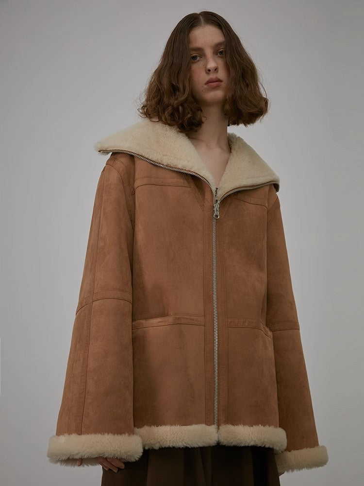 Person wearing a brown shearling coat with a white collar on a plain background