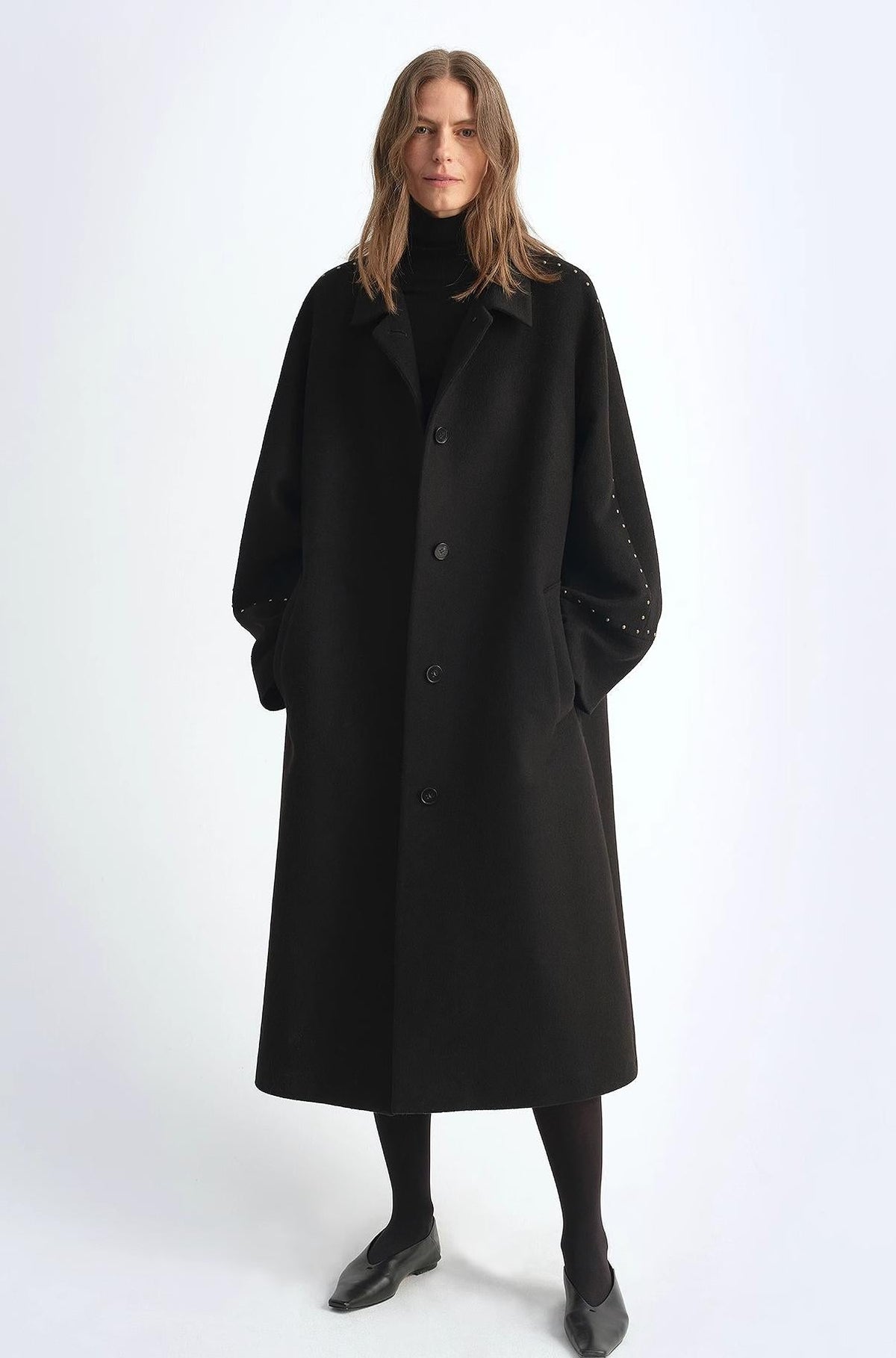 Person wearing a black coat on a white background