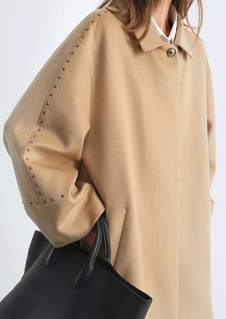 Beige coat with studded details on a white background