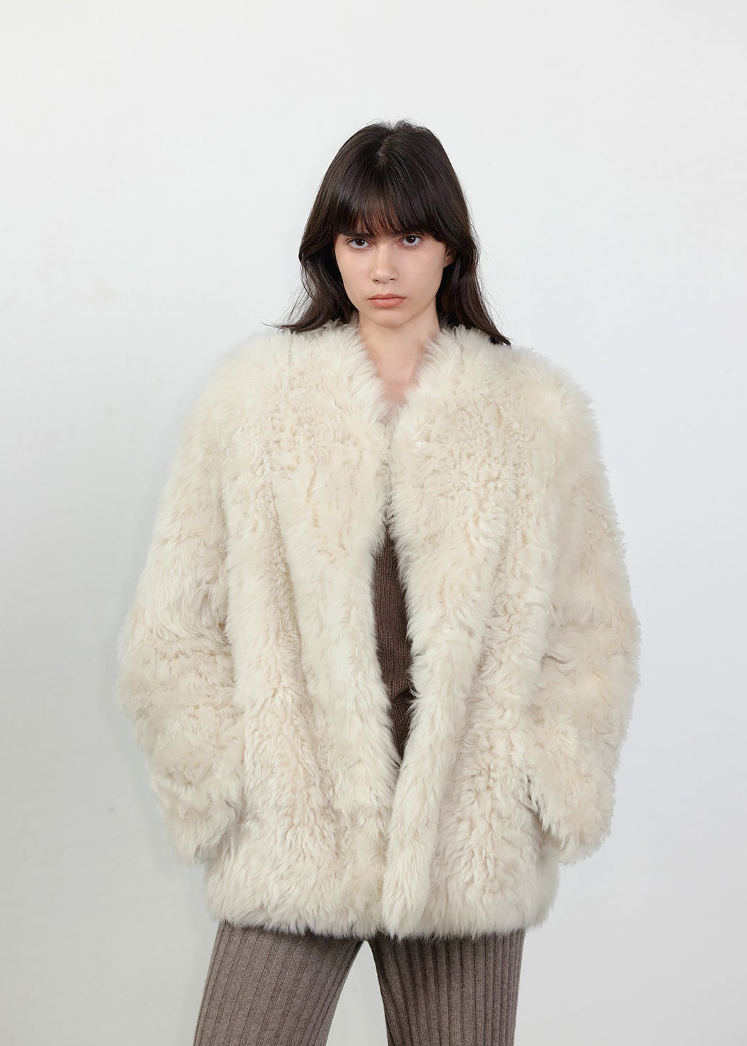Person wearing a fluffy white coat against a plain background