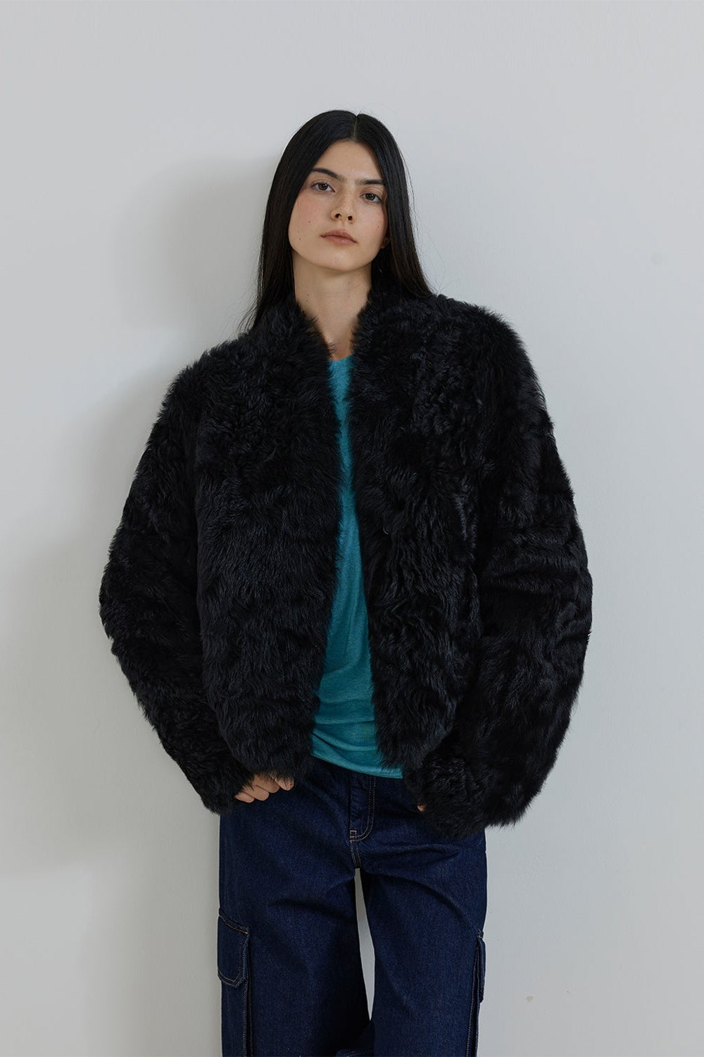 Person wearing a black fluffy jacket against a plain background