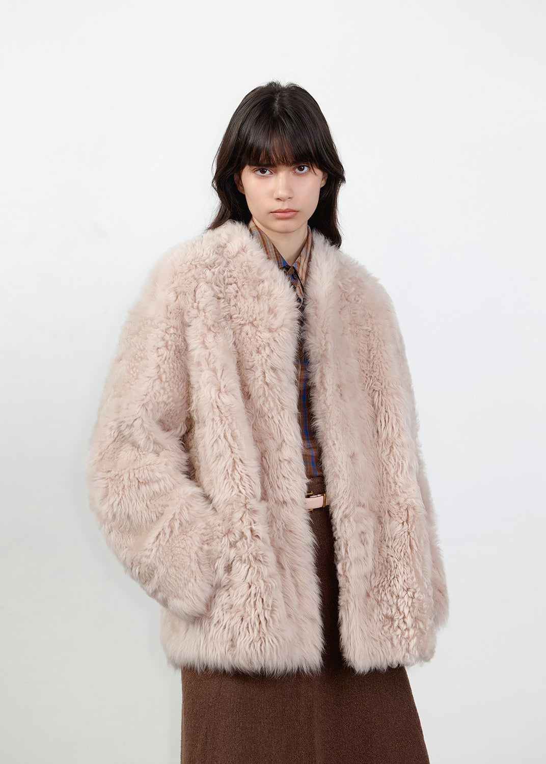 Person wearing a fluffy beige coat on a white background