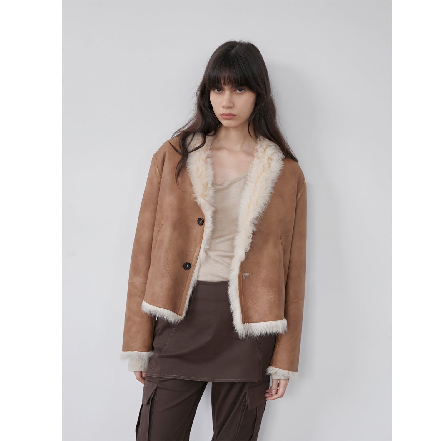 Person wearing a black fluffy jacket against a plain background