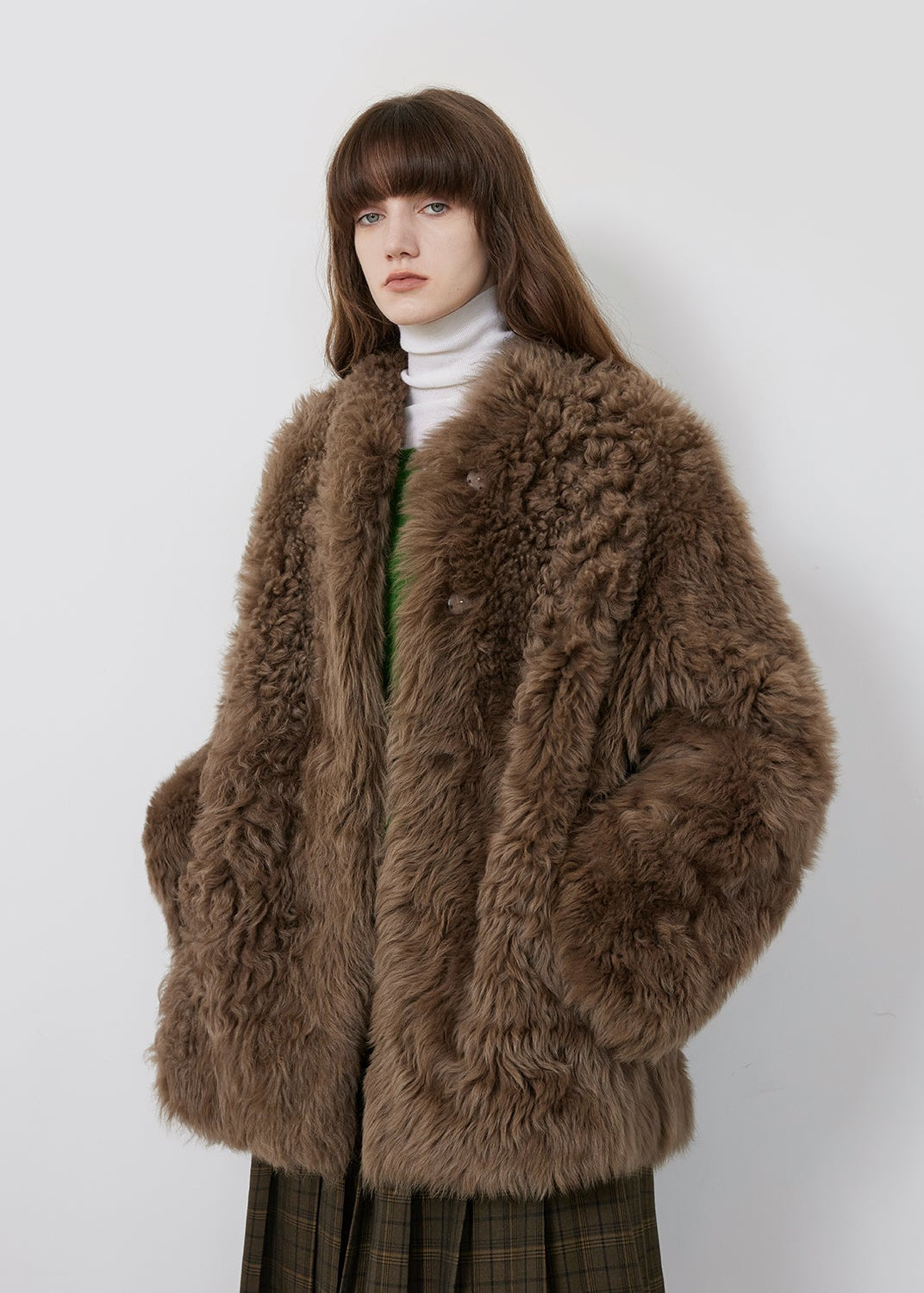 Person wearing a brown fur coat against a white background