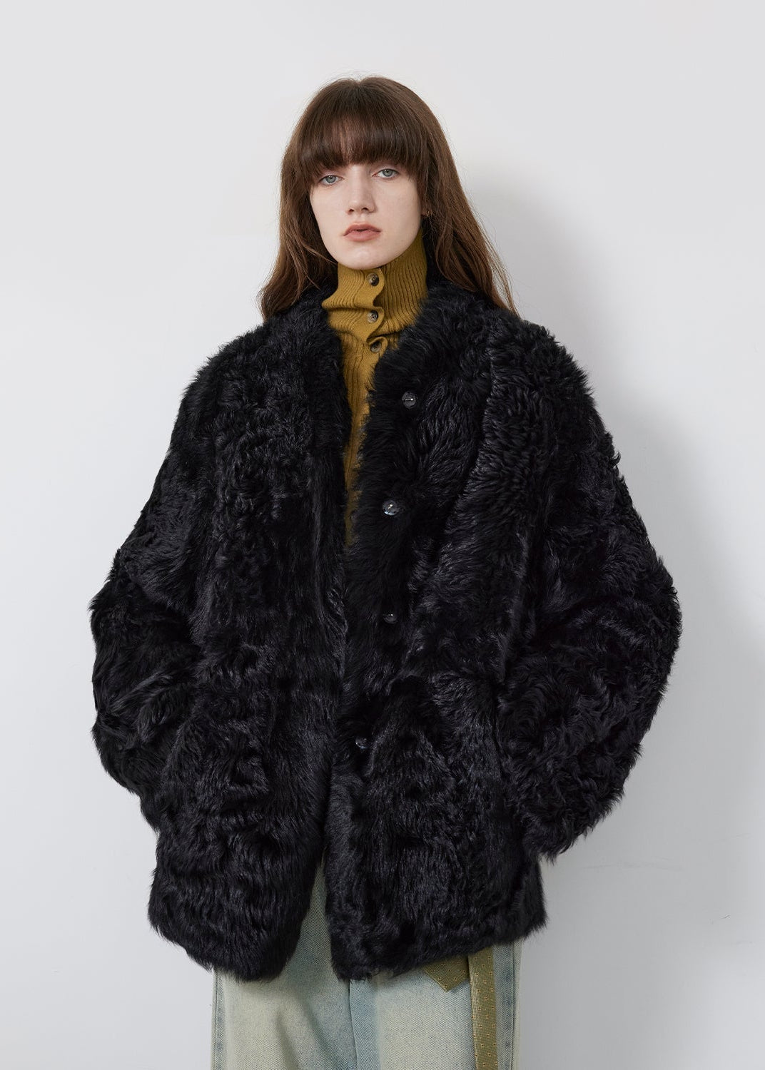 Person wearing a black fluffy coat against a white background